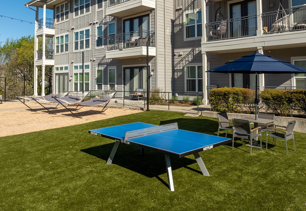 a ping pong table and chairs in front of an apartment building