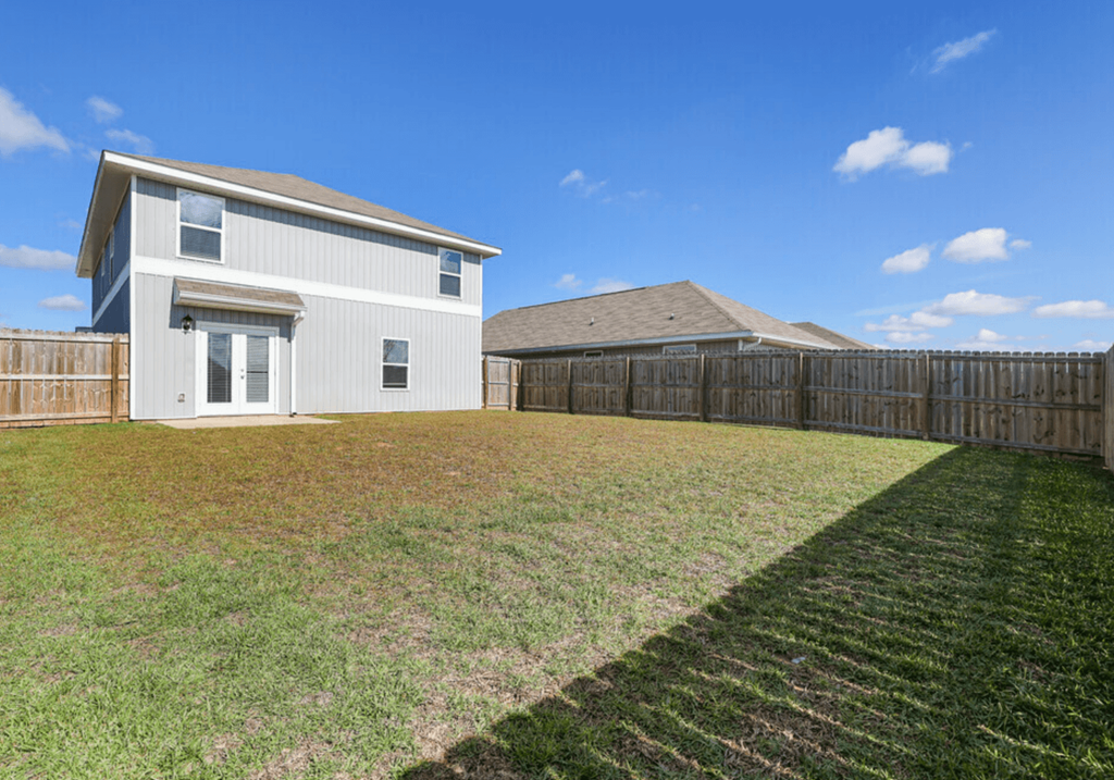 a backyard with a house and a wooden fence