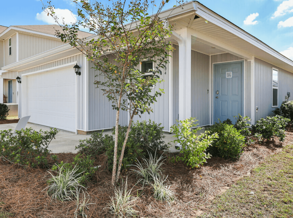 a house with a blue door and a tree in front of it