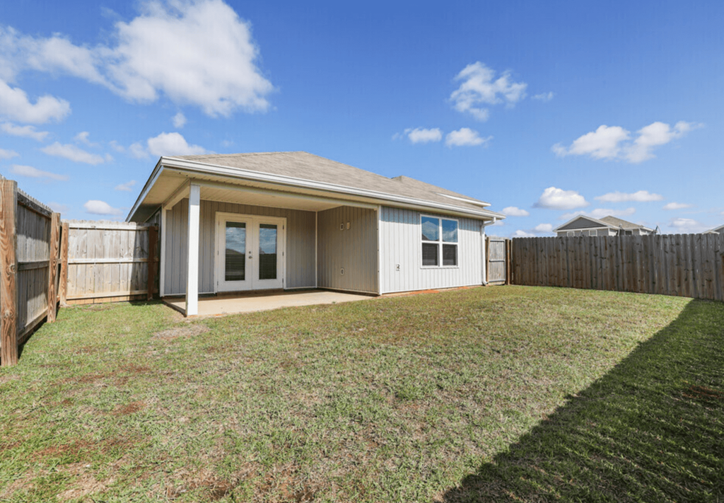 the backyard of a home with a lawn and a fence