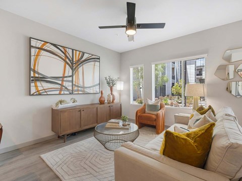 A living room with a large abstract painting on the wall, a white sofa, and a glass coffee table.
