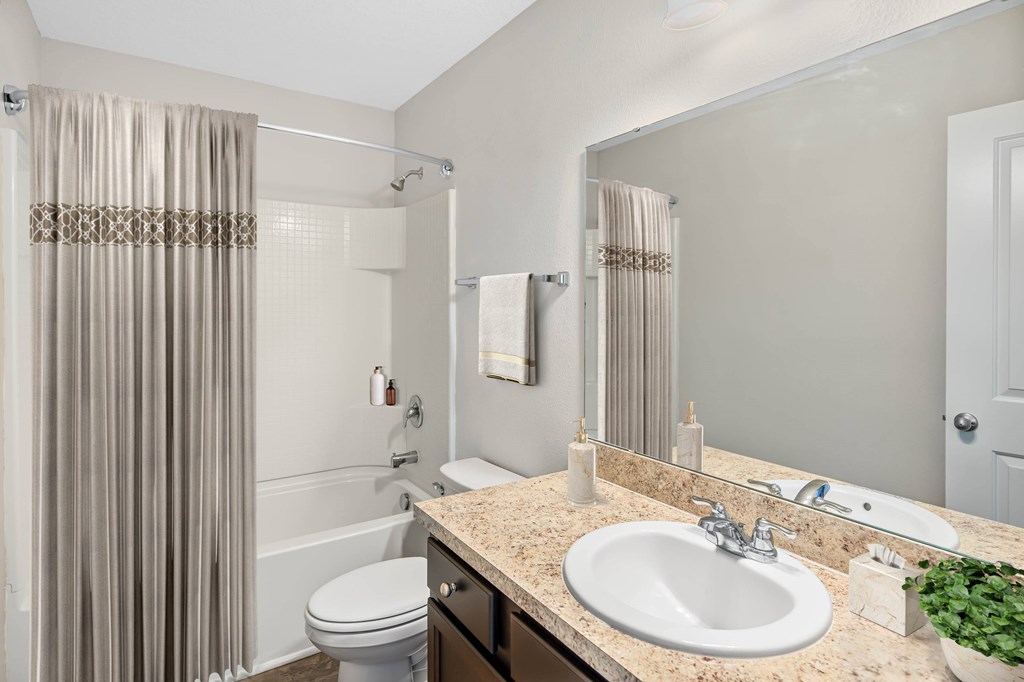 A bathroom with a toilet, sink, and shower curtain.