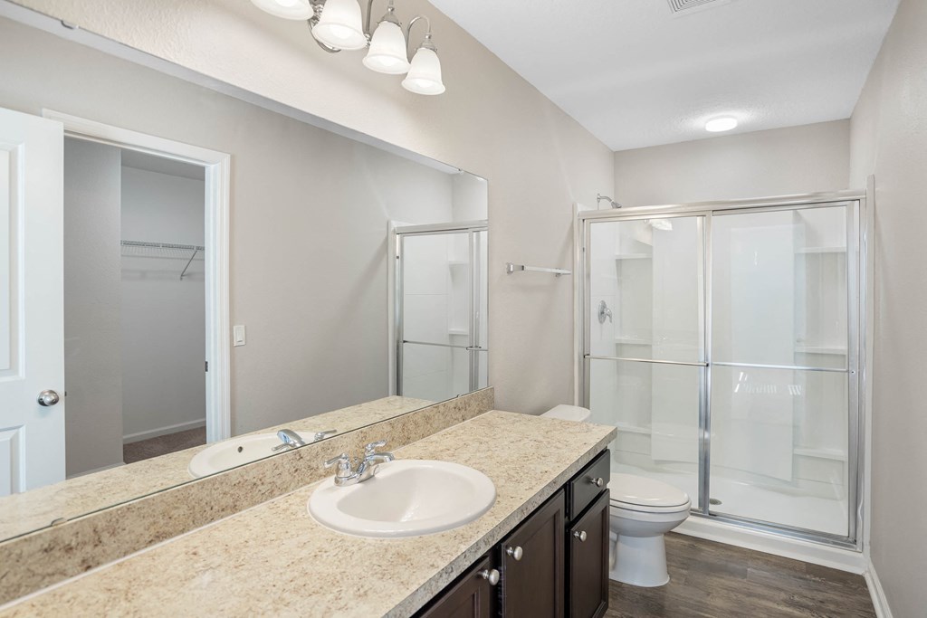 A bathroom with a sink, mirror, and shower.