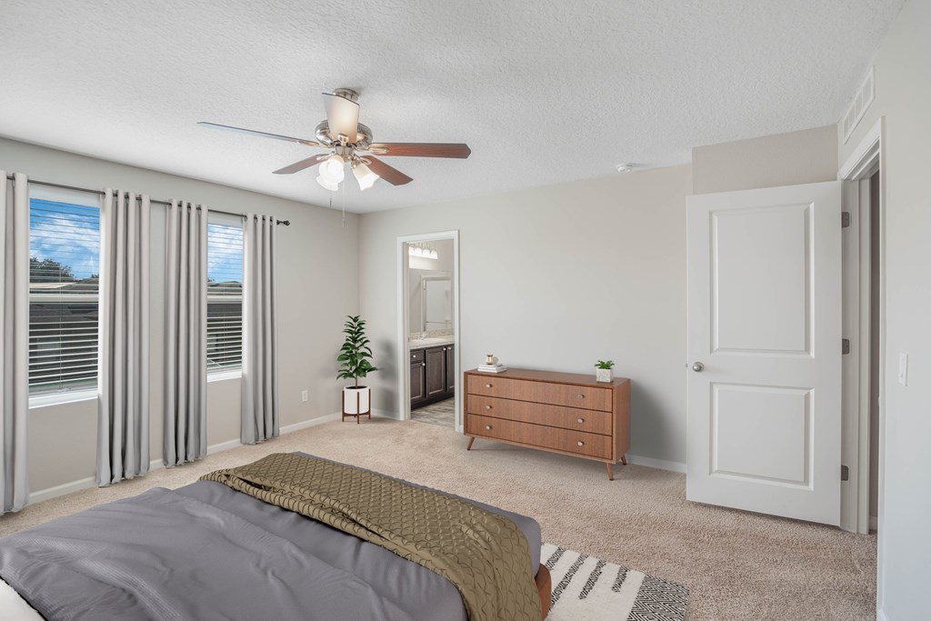 A bedroom with a bed, dresser, and sliding glass doors.