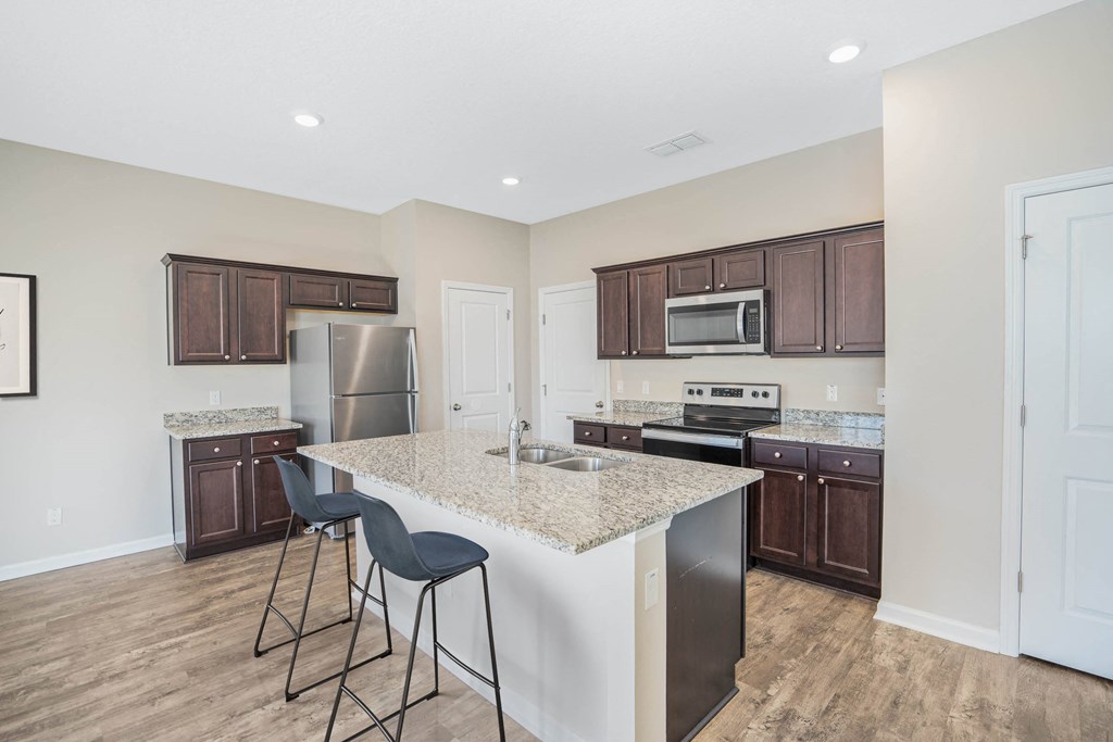 A kitchen with a white island and dark brown cabinets.