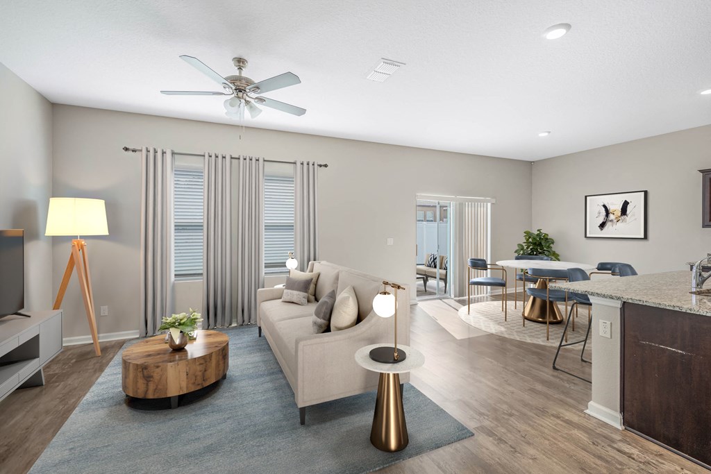 A modern living room with a grey sofa, a wooden coffee table, and a ceiling fan.