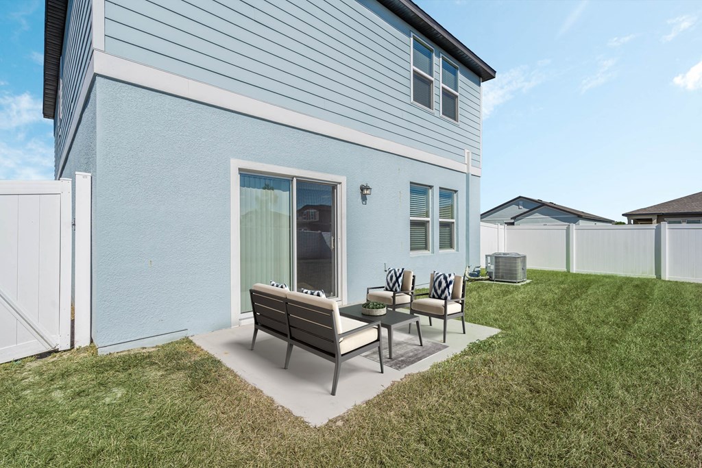 A blue house with a white fence and a patio with a table and chairs.