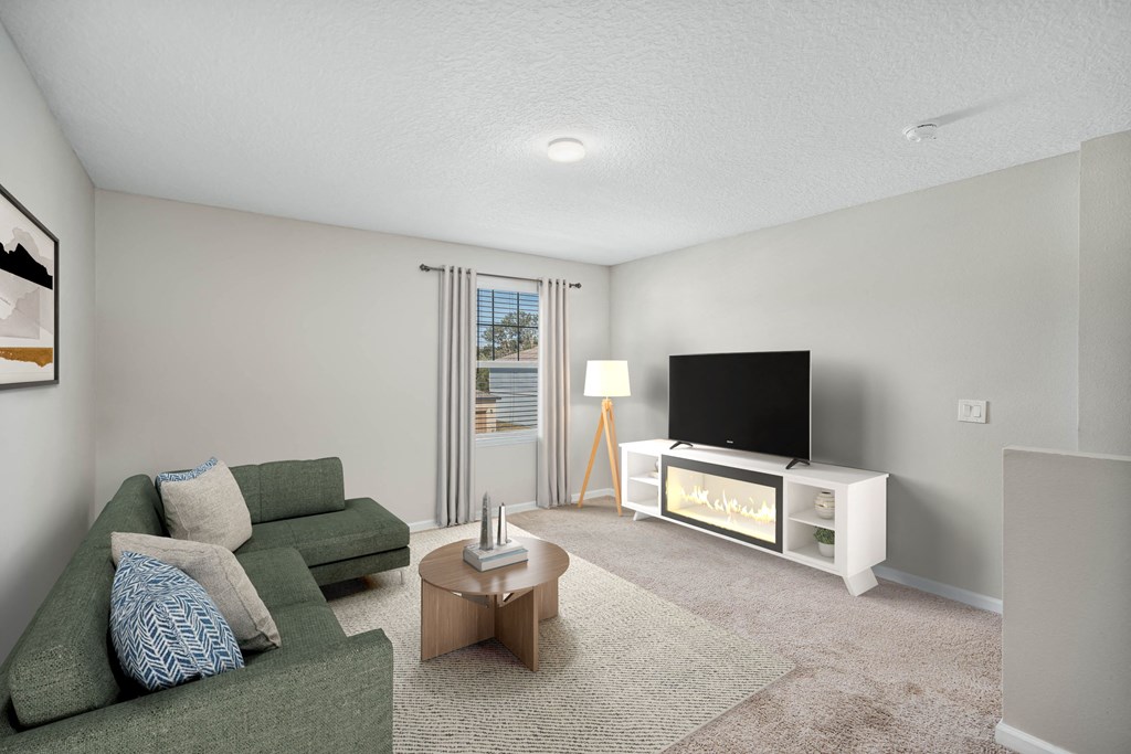 A living room with a green couch, a coffee table, and a television.