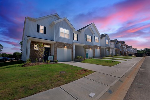 Row of modern townhouses at dusk with a pink and blue sky.