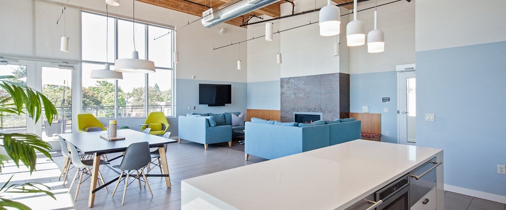 a living room with blue couches and chairs and a kitchen with a table and chairs
