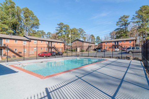 A swimming pool surrounded by a fence with a building in the background.