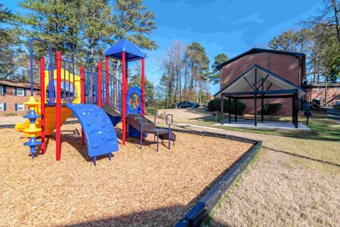 A playground with a blue and yellow slide and a red and yellow climbing frame.
