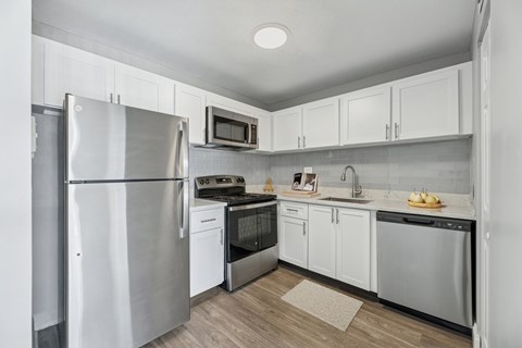 A kitchen with a refrigerator, microwave, oven, and sink.