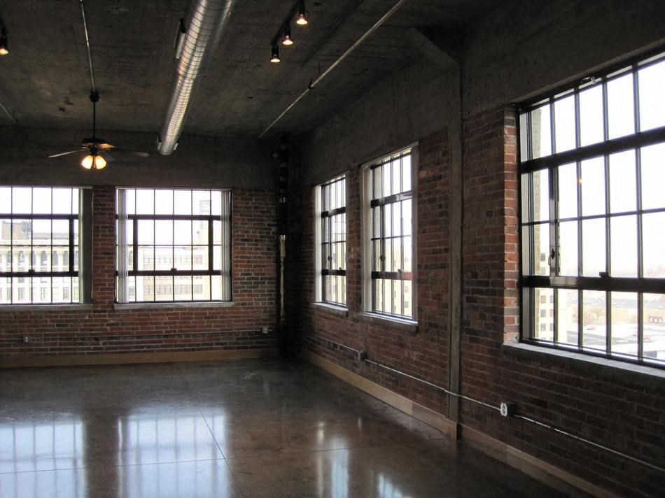 an empty room with large windows and a ceiling fan