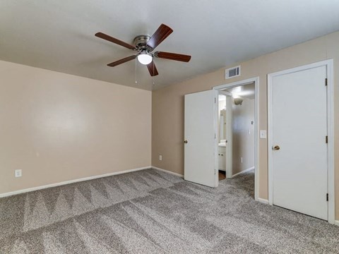 a bedroom with a ceiling fan and a door to a bathroom