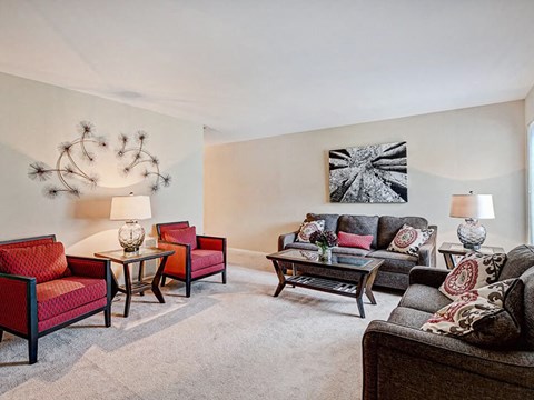 A living room with a grey carpet and a large painting on the wall.