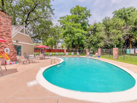 A small residential pool surrounded by a fence and trees.