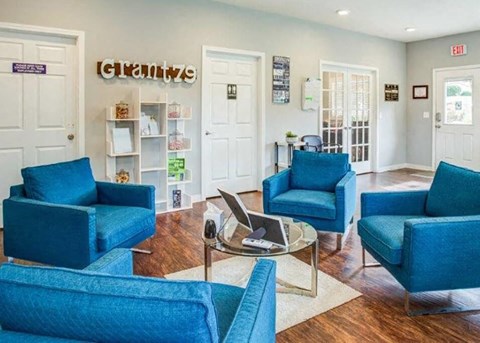 a living room with blue chairs and a laptop on a table