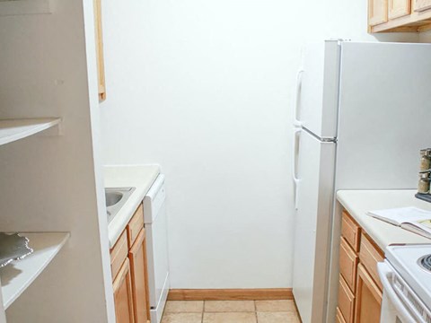 A white refrigerator stands in a kitchen with wooden cabinets.