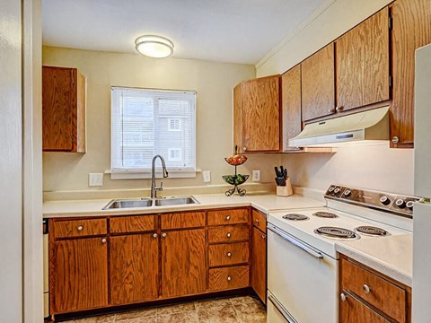 A kitchen with wooden cabinets and a white stove top oven.