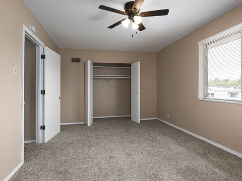 an empty bedroom with a ceiling fan and a closet