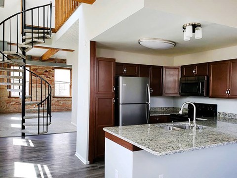 a kitchen with a marble counter top and a spiral staircase