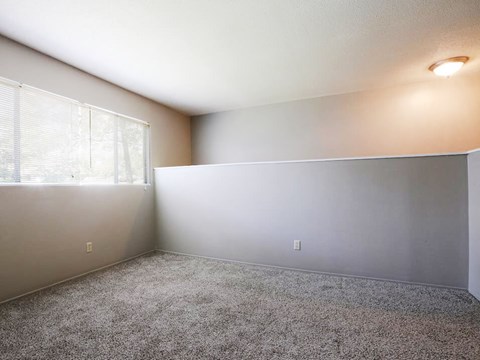an empty living room with a large window and carpet