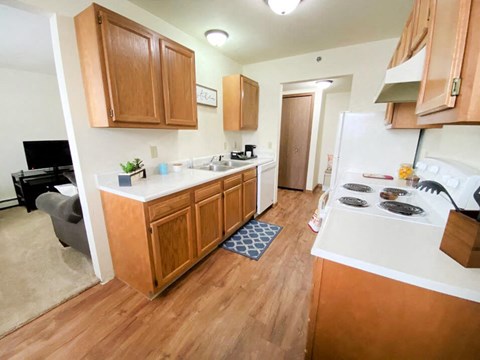 a kitchen and living room with wood floors and wooden cabinets