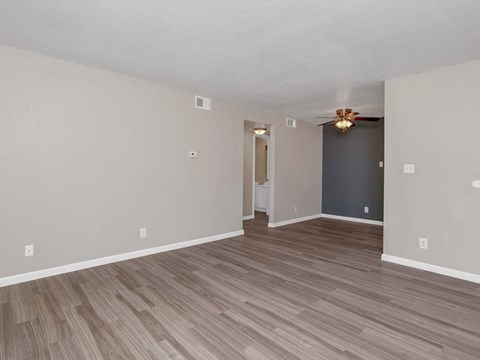 an empty living room with wood floors and a ceiling fan