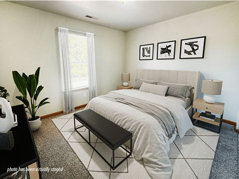 A bedroom with a large bed, a bench, and three framed pictures on the wall.