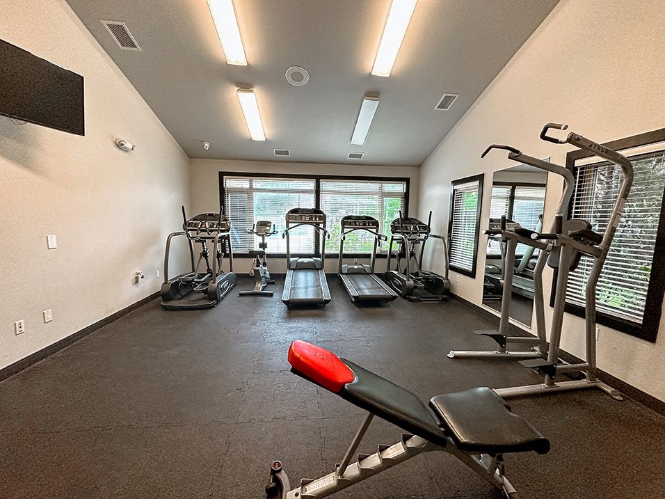 a gym with cardio equipment on the floor and windows