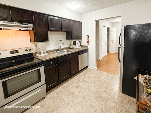 A kitchen with a black refrigerator and a stove with a silver oven.