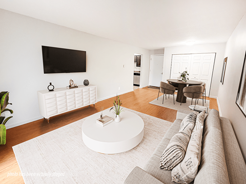A living room with a white couch and a television on the wall.