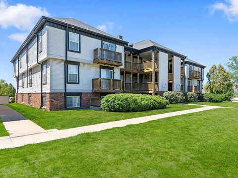 a sidewalk in front of an apartment building with green grass
