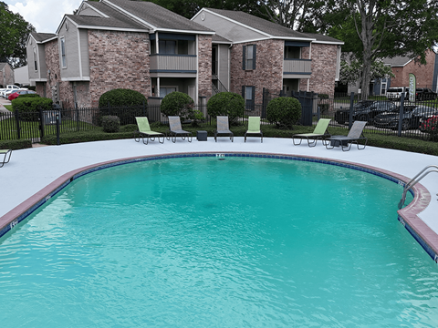 A swimming pool in front of a brick apartment building.