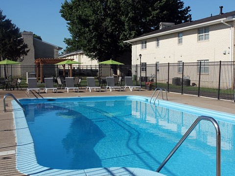 a swimming pool with chairs and a fence around it
