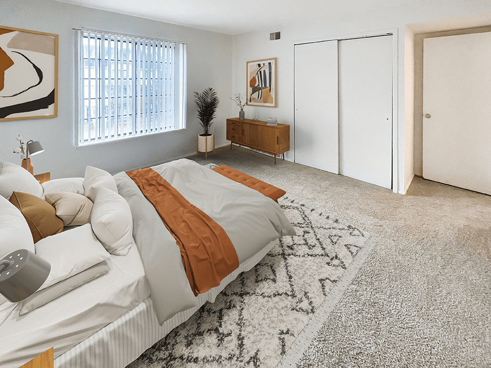 a bedroom with white walls and a white bed with an orange blanket
