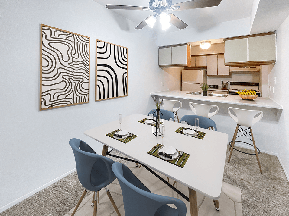 a dining area with a table and chairs and a kitchen in the background