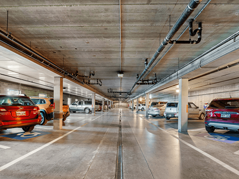 A parking garage with cars parked on both sides of the aisle.