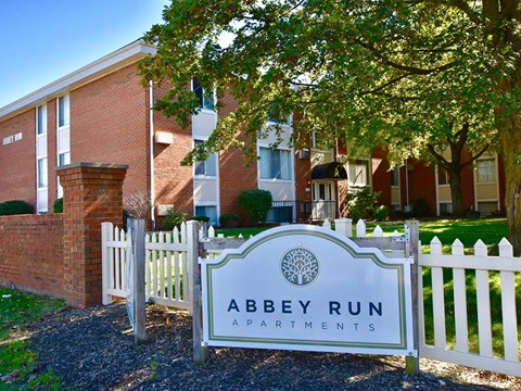 a white fence with a sign that reads abbey run apartments