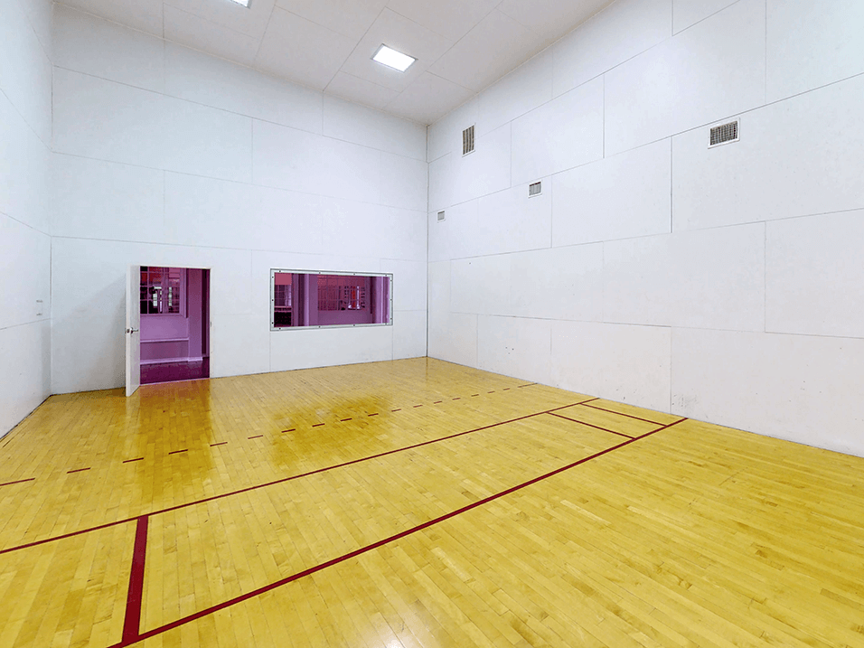 a Raquetball court with a wooden floor and white walls