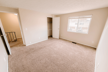 A room with a carpeted floor and a window.
