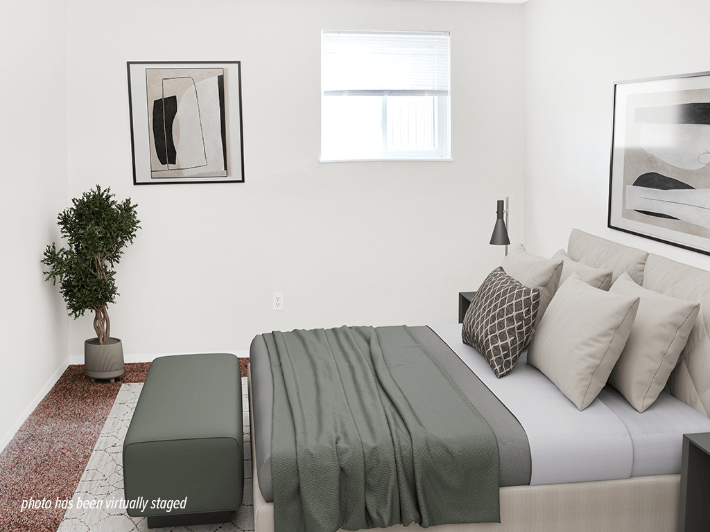 A bedroom with a bed, a bench, and a potted plant.