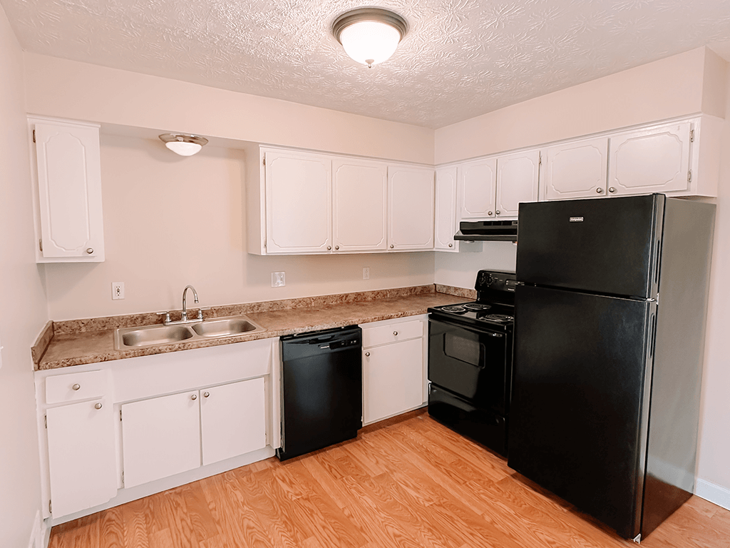 apartment kitchen with black appliances and white cabinets