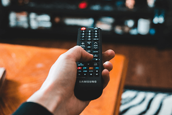 A hand is holding a Samsung remote control.