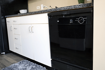 A black dishwasher with a digital display and a white cabinet.