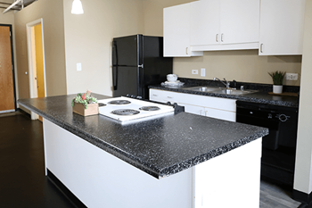 A kitchen with black and white appliances and a granite countertop.