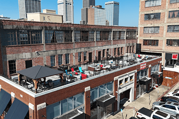 A rooftop patio with tables and chairs overlooks a city skyline.
