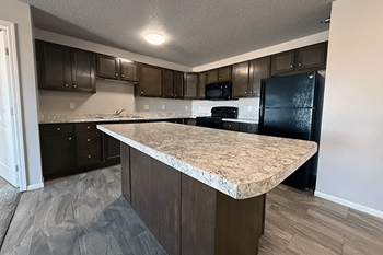 A kitchen with a granite countertop and black appliances.