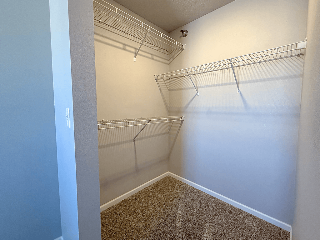 A walk-in closet with white walls and shelving.